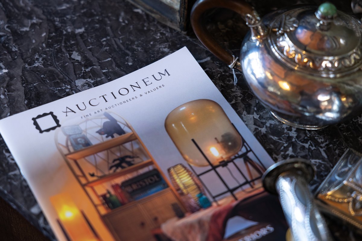 An Auctioneum catalogue among silver and antiques