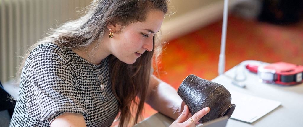 An Auctioneum valuer examining a bronze vase
